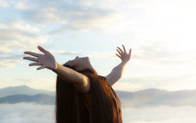 Worship God concept: Happy girl look up on blurred mountain sunrise background. Ai Yerweng,...