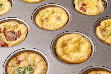 Egg bites with broccoli and pieces of bacon in a metallic gray form