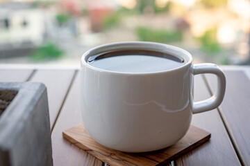 White cup of black coffee on a wooden table.