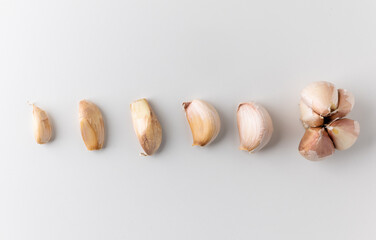 Fototapeta na wymiar Garlic cloves and pieces of raw garlic on isolated white background. Arranging from small to mature.
