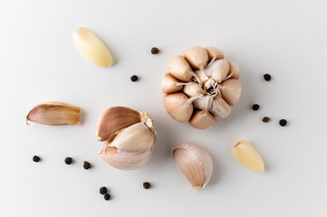 Top view Garlic bulbs Garlic cloves and pieces of raw garlic with black pepper or pepper corns. Garnish and food ingredients arranging on isolated white background.