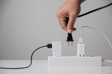 Hand holding Electric plug put on multiple socket. Electrical equipment, electrical wires and power...