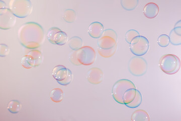 Beautiful shiny colorful soap bubbles floating on soft pink texture background. Abstract, Natual fresh summer background.