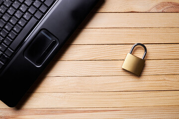 privacy data protection. above view for a black laptop and golden padlock over wooden desk. cyberspace safety technology concept