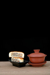 Moon cakes broken in half and a bowl of tea in front of a black background