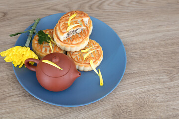 Moon cakes, a pot of tea, and a chrysanthemum on the plate