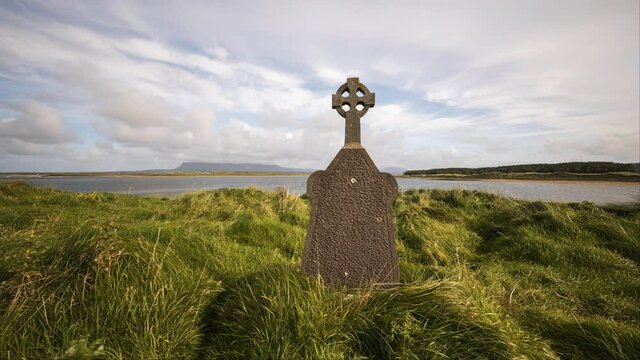 Motion time lapse of historical cemetery on the coast of Ireland with hills in the distance and moving clouds in the sky.