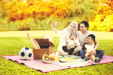 Muslim family take selfie while picnicking at autumn