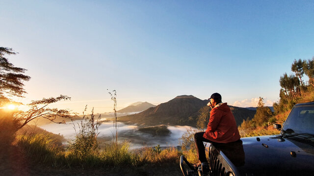 Man sit on car hood while enjoy mount batur view
