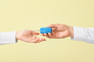 Male and female hands with car key on color background