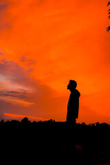 Silhouette of a person standing alone with beautiful sunset in the background