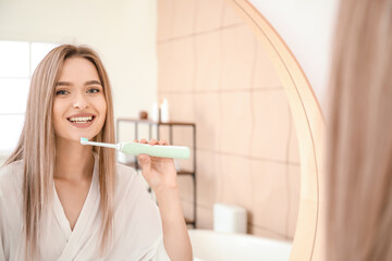 Young woman brushing teeth in bathroom