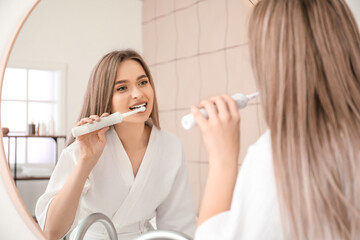 Young woman brushing teeth in bathroom