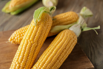 Fresh corn cobs on wooden background