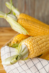 Basket with fresh corn cobs on table