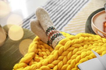 Beautiful young woman in socks and with warm plaid relaxing at home