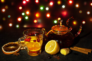 Immunity tea with lemon, ginger and cranberry and cinnamon with a glass kettle and cup. Christmas atmosphere.