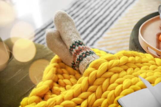 Beautiful young woman in socks and with warm plaid relaxing at home