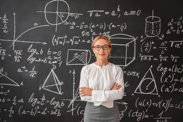 Mature maths teacher near blackboard in classroom - obrazy, fototapety, plakaty