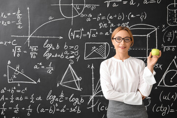 Mature maths teacher near blackboard in classroom
