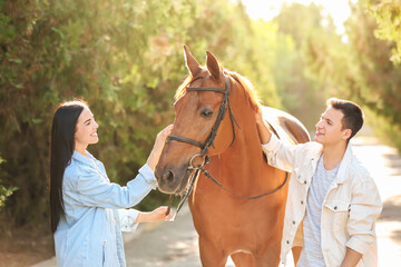 Young couple with cute horse outdoors
