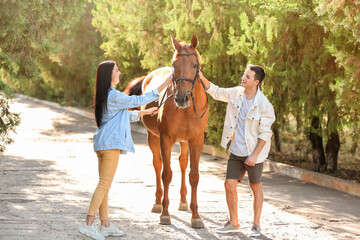 Young couple with cute horse outdoors