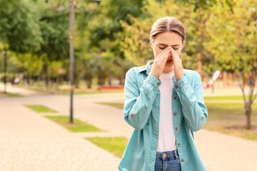 Young woman suffering from allergy outdoors - obrazy, fototapety, plakaty