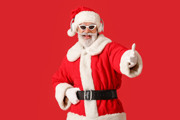 Fototapeta na wymiar Cool Santa Claus listening to music on color background