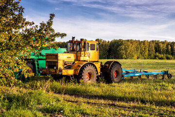 Wheeled agricultural tractor with harvesting equipment on an field