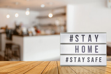 Lightbox sign with text hashtag #STAY HOME and #STAY SAFE blurred coffee shop background. COVID-19. Stay home save concept.