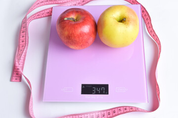 There are two apples on the electronic scale, and around them is a measurement for measuring the waist