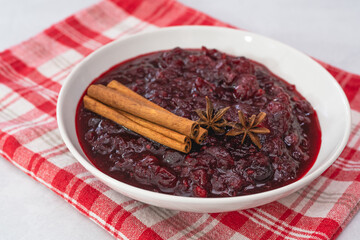 Cranberry sauce, cinnamon, anise star close up in a bowl on kitchen table