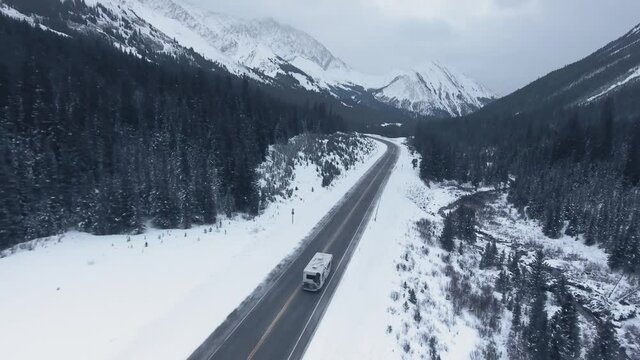 Drone chasing RV crossing the continent through high mountains and forest in Kananaskis, Alberta, Canada
