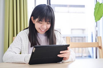 リビングでタブレットを見る日本人女子中学生