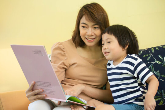 Asian Mother Is Reading A Storybook To Her Son.