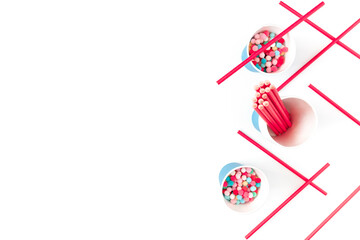 The concept of preparing for a party, event, celebration. Blue paper cups, red straws and colorful balls are on a white background. Template for christmas, new year, invitation, banner. Flat lay.