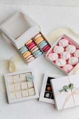 Lots of sweets in square boxes. Macarons, turkish delight, zefir, wrapped candy