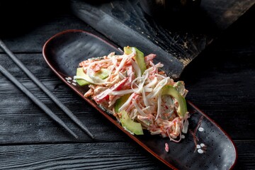 Chinese salad with avocado, fresh vegetables, fresh herbs and creamy dressing. Black background and black decor.