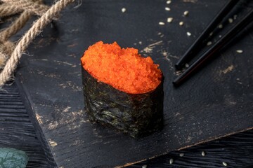 Gunkan Maki with masago capelin caviar. Black background and black decor.