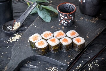 Classic Japanese sushi roll with salmon. Black background and black decor.