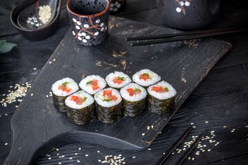Classic Japanese sushi roll with vegetables. Black background and black decor.