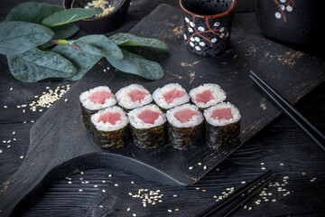 Classic Japanese sushi roll with tuna. Black background and black decor.
