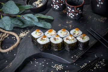 Classic Japanese sushi roll with eel and cucumber. Black background and black decor.