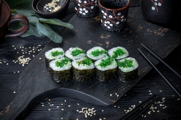 Classic Japanese sushi roll with seaweed. Black background and black decor.