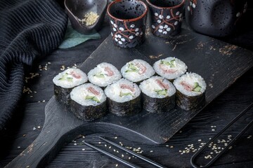 classic sushi roll with tuna, cream cheese and cucumber. Black background and black decor.