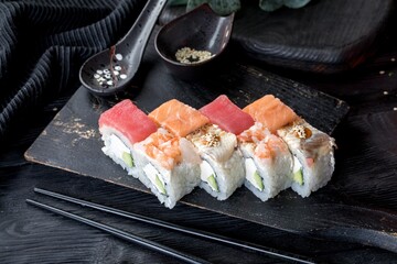 Assorted four types of rolls. With tuna, salmon, shrimps and eel. Black background and black decor.