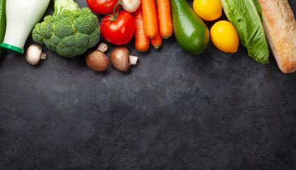 Various vegetables, bread and milk on stone table