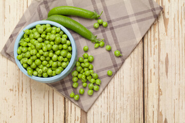 Top view of green peas in bowls on white wooden background