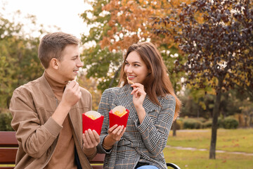 Young couple eating french fries in park