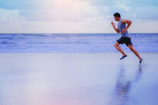 Man running athletes at the beach with sunset background.	